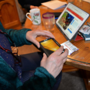 A persons hand doing some usability testing with a magnifier