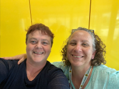 Chandra and Sally Brittnell smiling in front of a bright yellow background