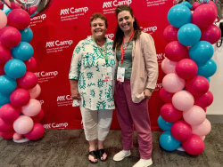 Chandra and Maia Miller standing in front of the A11yCamp banner