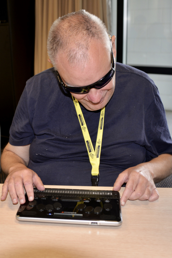 Man using a Braille device to access emails