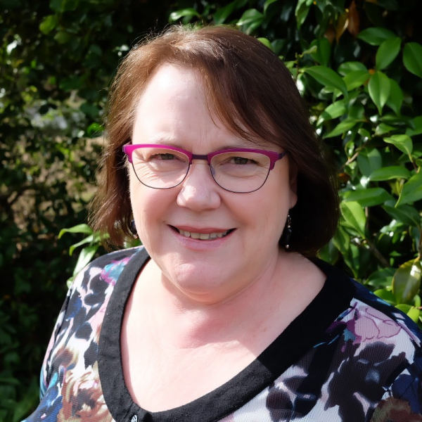 Katherine Baker, the new Access Advisors Executive Assistant, Katherine is outside in the sunshine in front of some leafy green trees