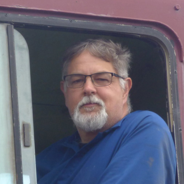Kevin driving a red train, looking out the open window