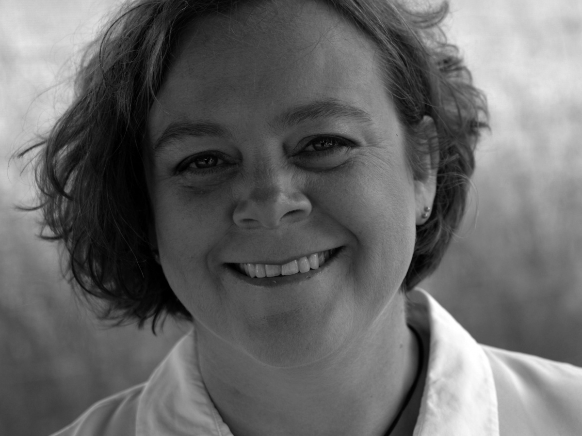 Chandra's face and shoulders, she looks relaxed and is smiling. Image is in grayscale.