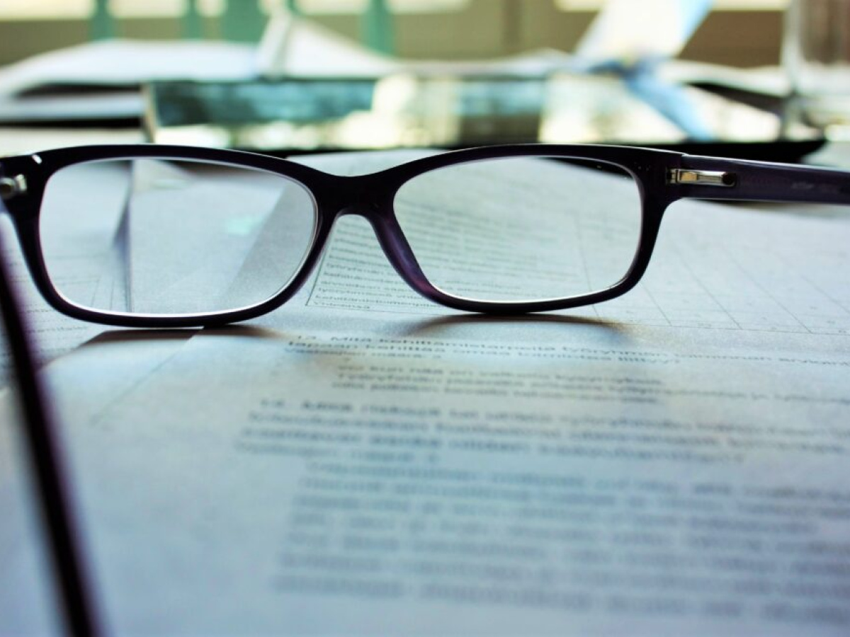 Pair of reading glasses resting on top of a stack of documents.
