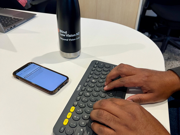 Hands typing on a bluetooth keyboard with mobile phone nearby