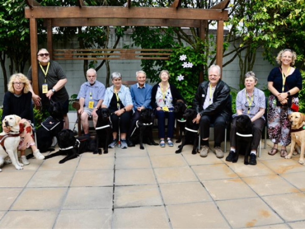 Group of guide dogs and their handlers sitting in the courtyard at the Deafblind conference two years ago