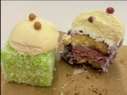 Green and purple lamington's filled with coloured cream and topped with whipped cream.